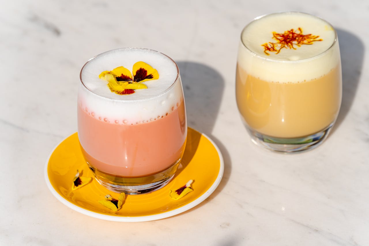 Two vibrant floral tea lattes with edible flowers, perfect for a refreshing treat.